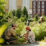 Caucasian Man and Young Girl Planting Shrubs in Urban Community Garden