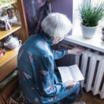 Woman holding cash in front of heating radiator. Payment for heating in winter. Selective focus.